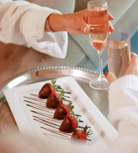 Photo of the Galentine's Day Yoga Brunch event at The OH! Spa featuring two champagne glasses, chocolate-dipped strawberries, and a celebratory toast.