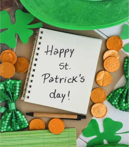 St. Patrick's Day celebration concept with a note reading 'Happy St. Patrick's day!', surrounded by green themed items including shamrocks, a hat, and chocolate gold coins.